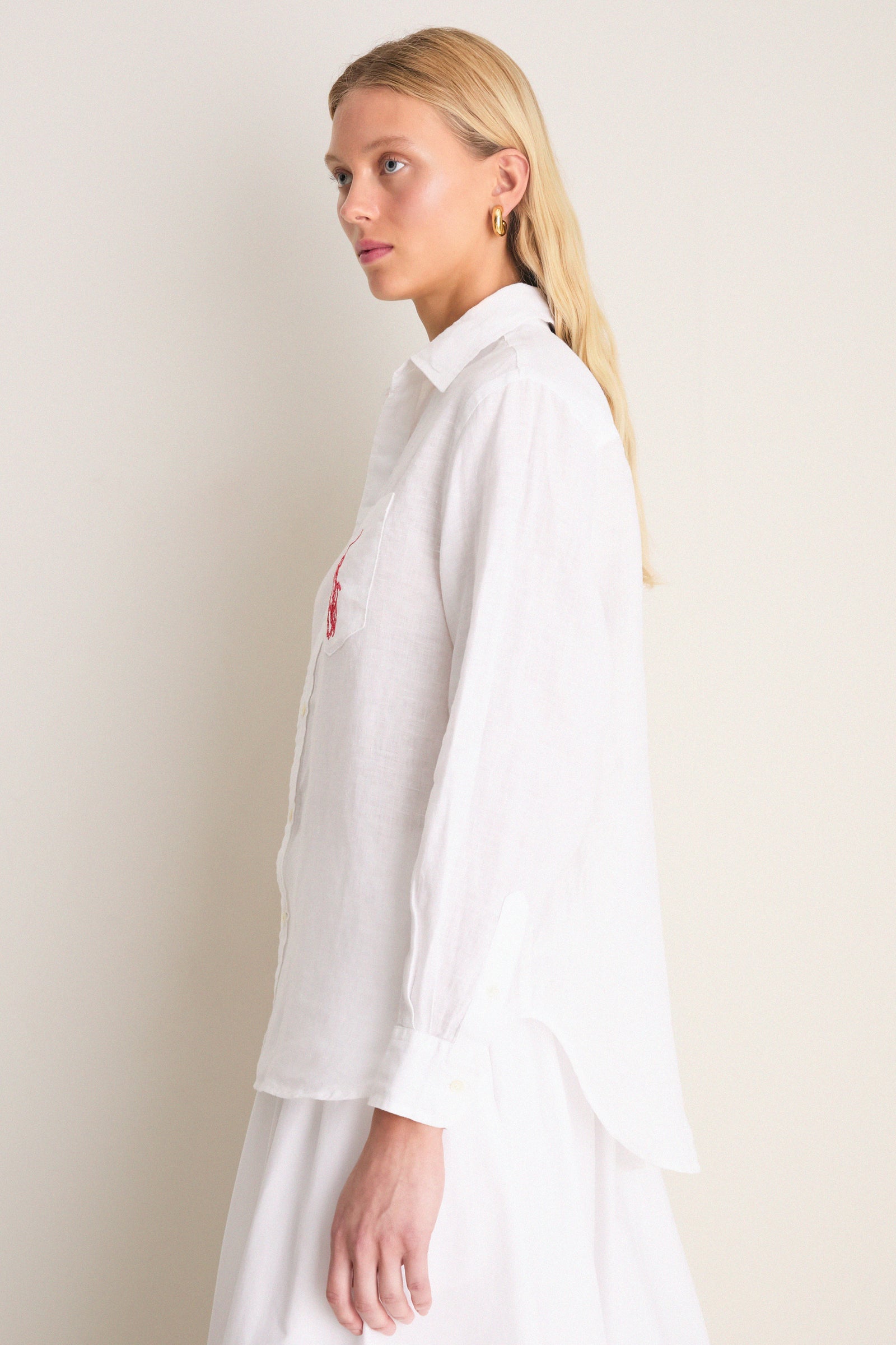 Classic Oxford White Linen Button Down modeled side-profile, showcasing relaxed fit, point collar, shell buttons, and embroidered detail on chest pocket for an effortless, high-end style.