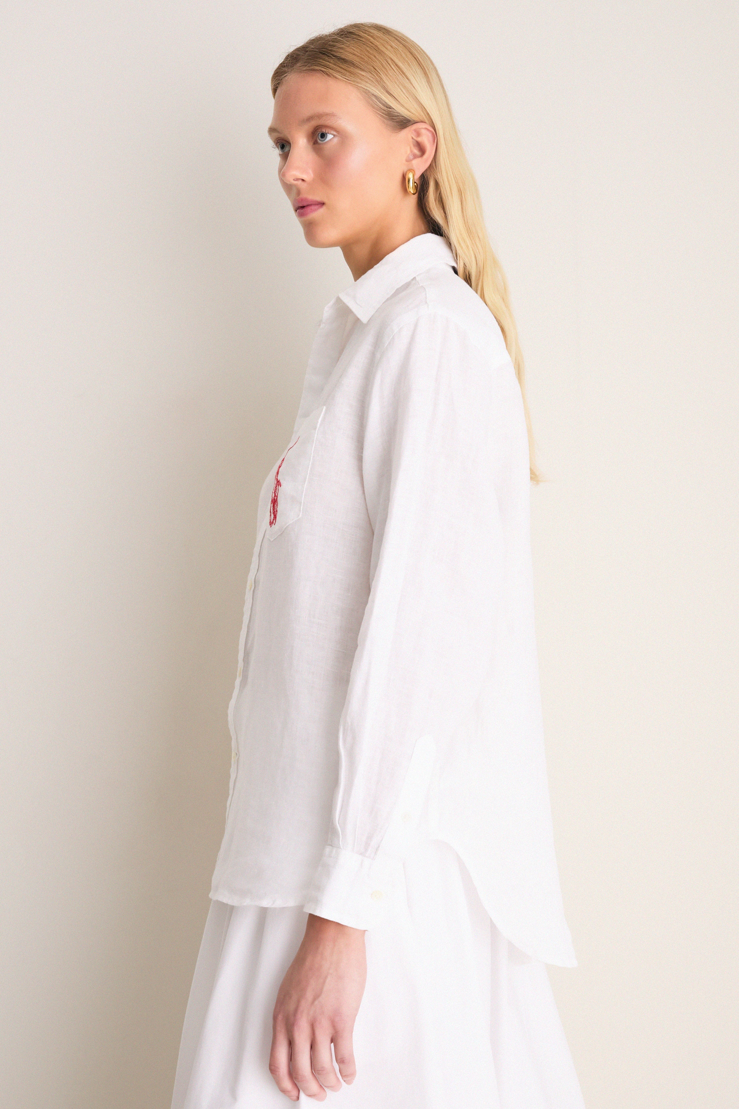 Classic Oxford White Linen Button Down modeled side-profile, showcasing relaxed fit, point collar, shell buttons, and embroidered detail on chest pocket for an effortless, high-end style.