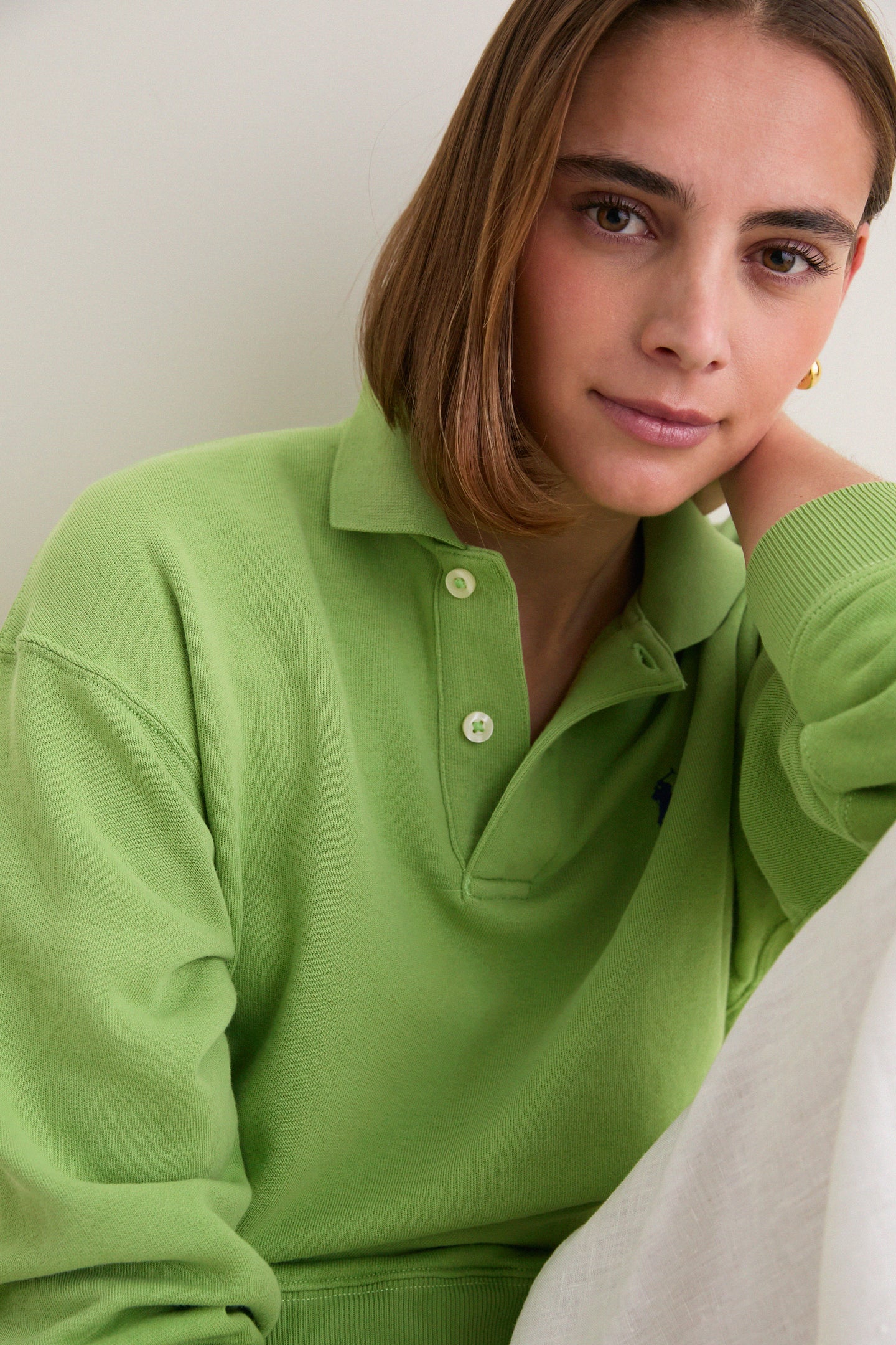 Young woman wearing Parakeet Green Island Fleece Knit Polo, a classic, effortless pullover with a relaxed fit, ribbed cuffs, and iconic embroidered Pony, exuding fun, high-end style.