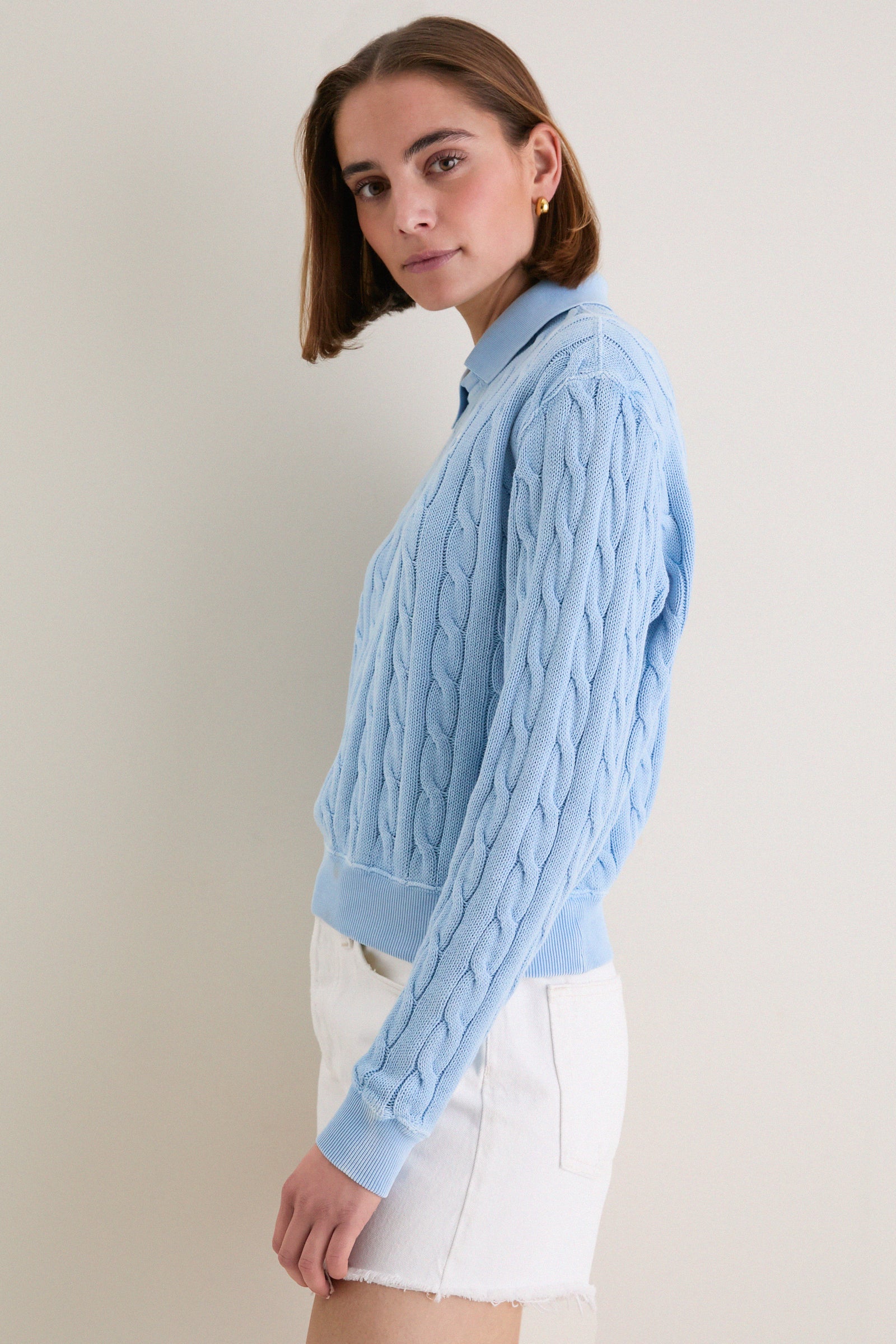 Young woman in profile wearing Polo Ralph Lauren's Chambray Blue Cotton Knit Polo, showcasing its classic cable-knit design and effortless, high-end style with a vintage-inspired finish.