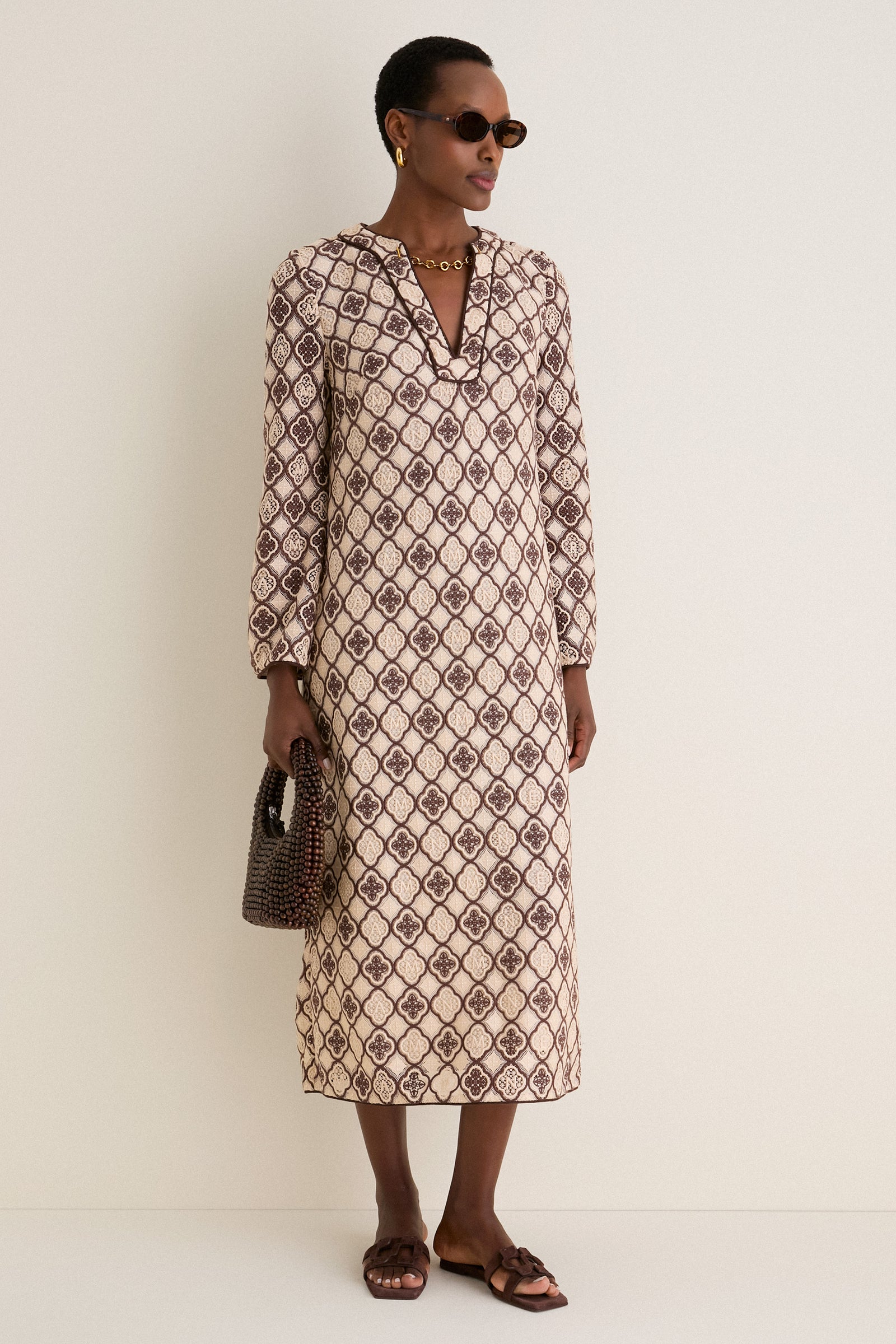 Model wears Brown Tortoise Lyric Leigh Sunglasses, embodying classic elegance with an effortless vibe, paired with a patterned dress, gold accessories, and a chic handbag.