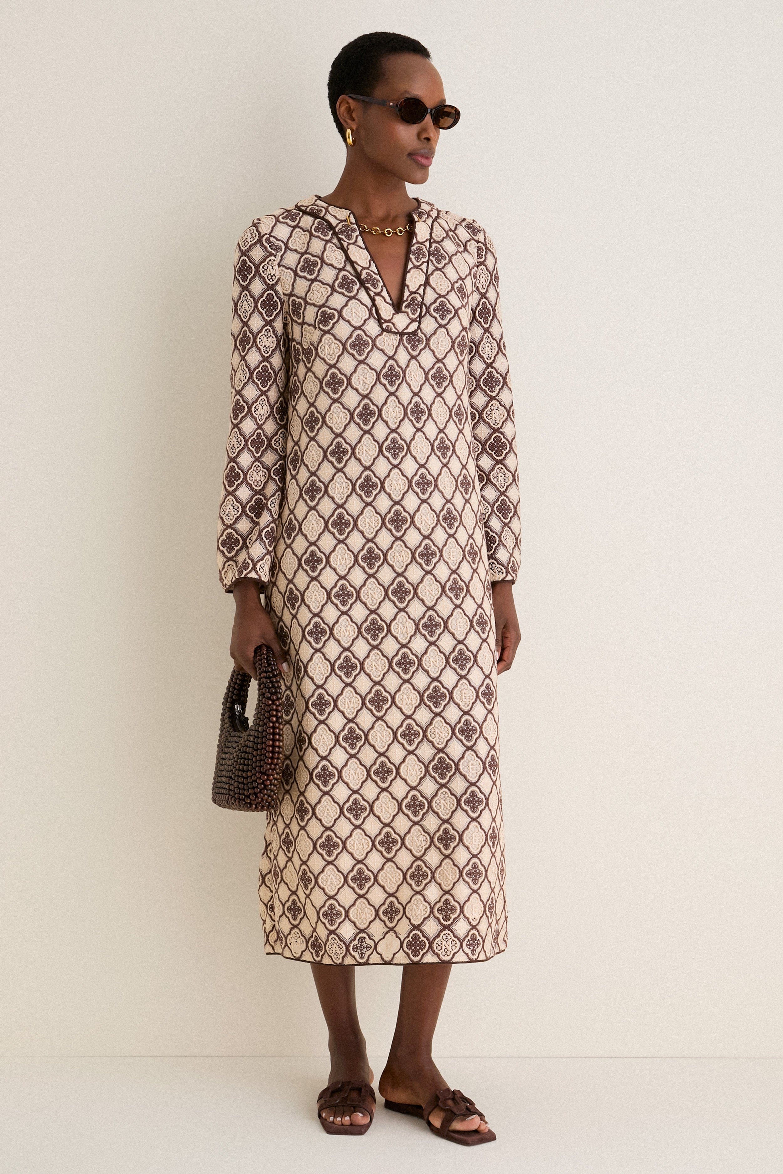 Model wears Brown Tortoise Lyric Leigh Sunglasses, embodying classic elegance with an effortless vibe, paired with a patterned dress, gold accessories, and a chic handbag.