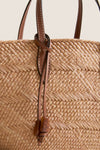 Nuez and Cognac Small Trapeze Basket: Classic woven straw tote with leather accents and drawcord details, offering an effortless, high-end style perfect for fun, warm-weather outings.