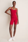 Model wearing Red Compression Spandex Mac Bike Short with a sporty camisole, embodying effortless style and comfort; perfect for athleisure, featuring a high-rise, compression fit, and reflective logo.