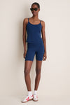 Model wears Navy Compression Spandex Mac Bike Short with matching tank, styled effortlessly with a classic gold chain, perfect for a fun, high-end athleisure look.