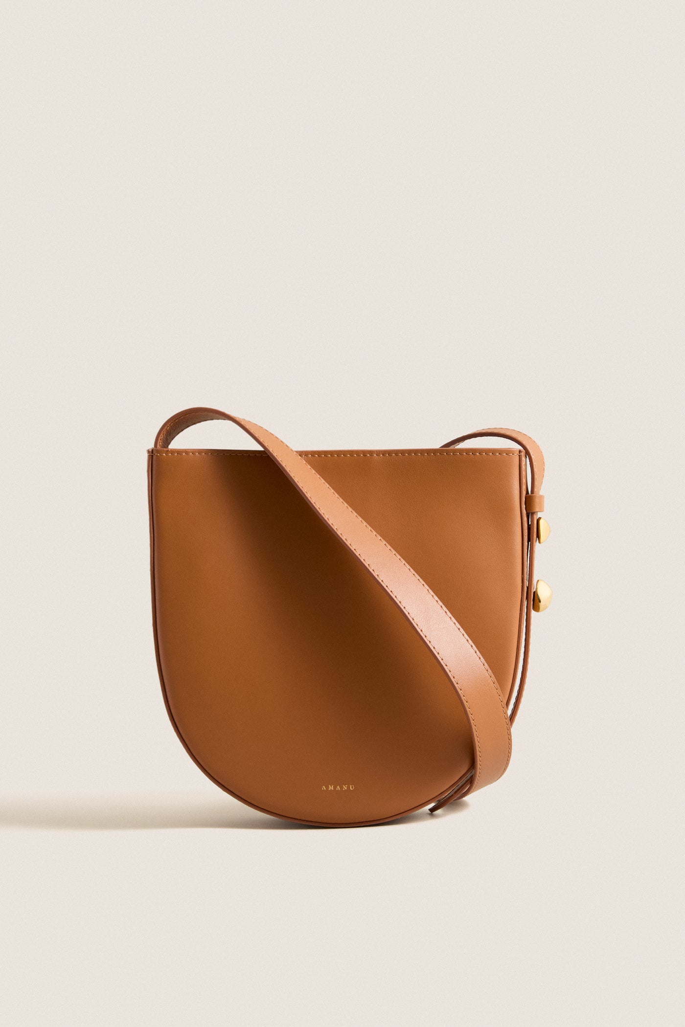 Classic Cognac Leather Nigeria Crossbody with gold-tone hardware and adjustable strap, exuding effortless elegance and high-end craftsmanship, perfect for fun, versatile styling.