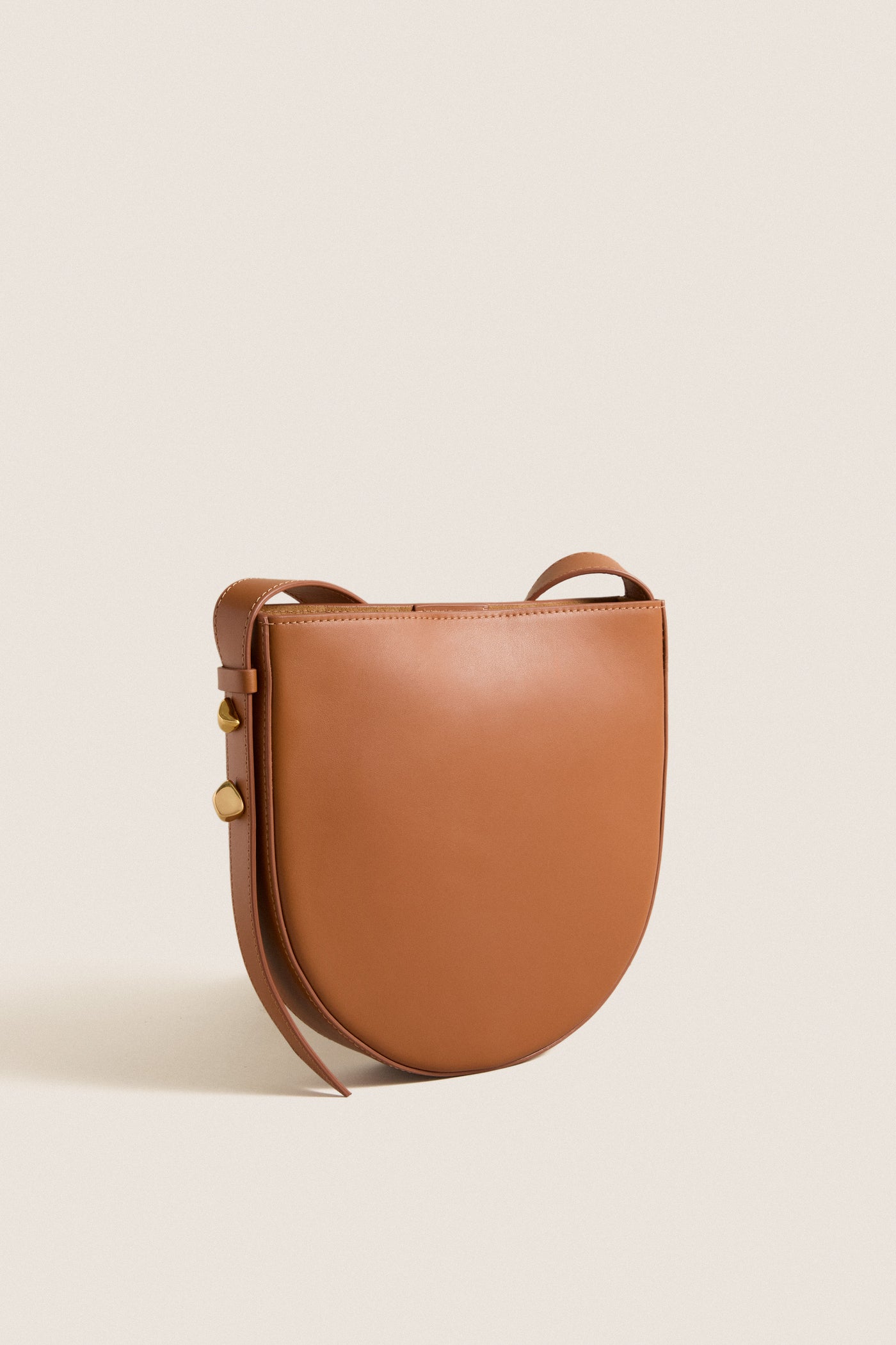 Classic Cognac Leather Nigeria Crossbody, a high-end, effortless saddle-bag style with gold-tone studs and slim strap, perfect for fun, versatile day-to-night wear.