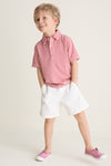 Young blond boy wearing the classic Nantucket Red and Creme Le Club Polo with red and white stripes, exuding effortless fun and high-end style.