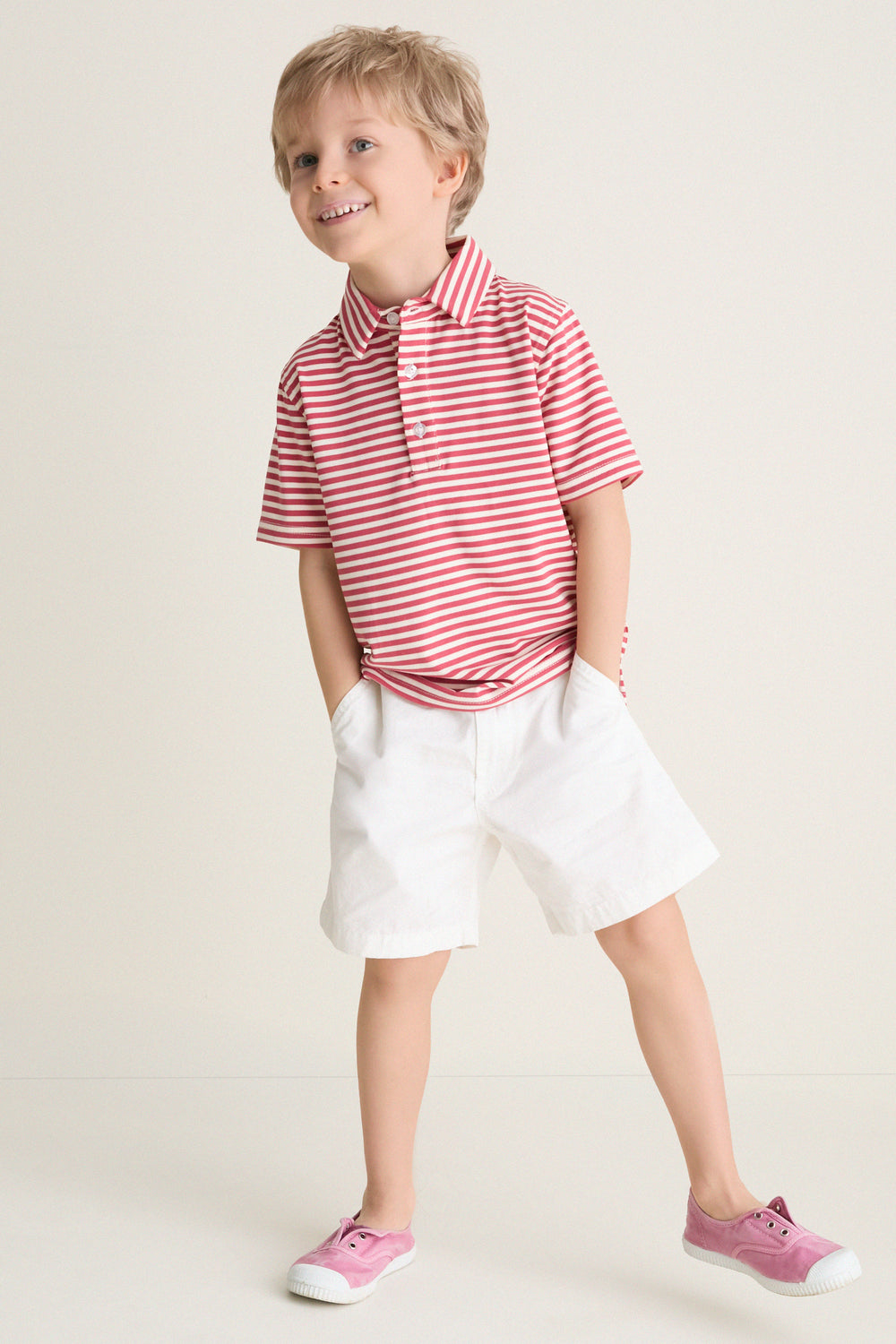 Young blond boy wearing the classic Nantucket Red and Creme Le Club Polo with red and white stripes, exuding effortless fun and high-end style.