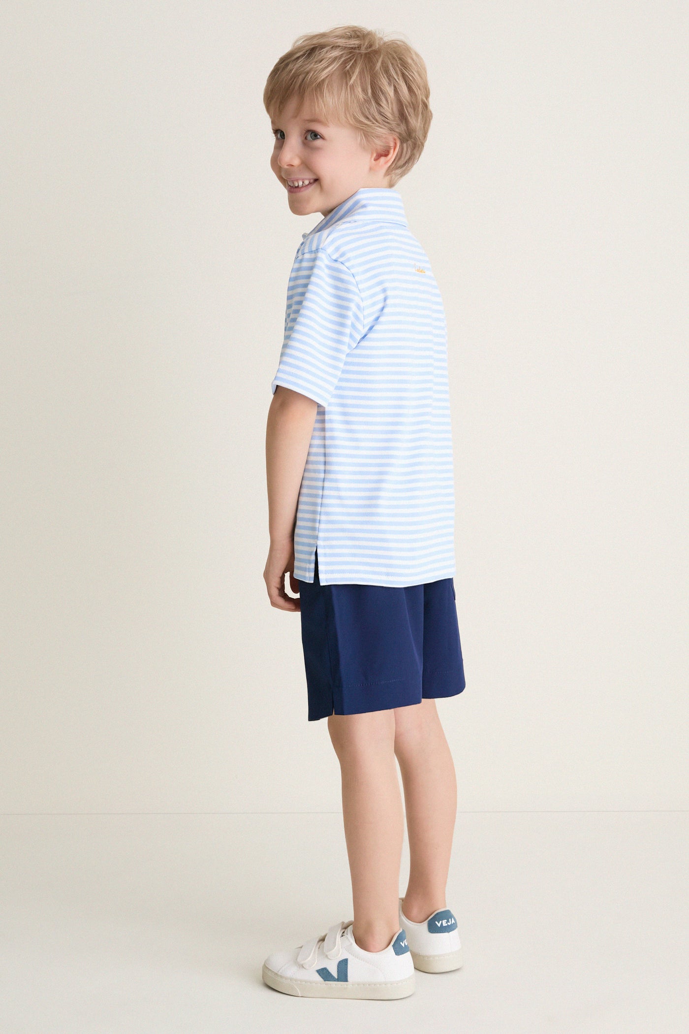 Young boy models the classic Bachelor's Blue and White Le Club Polo, showcasing its effortless style and fun, high-end design.