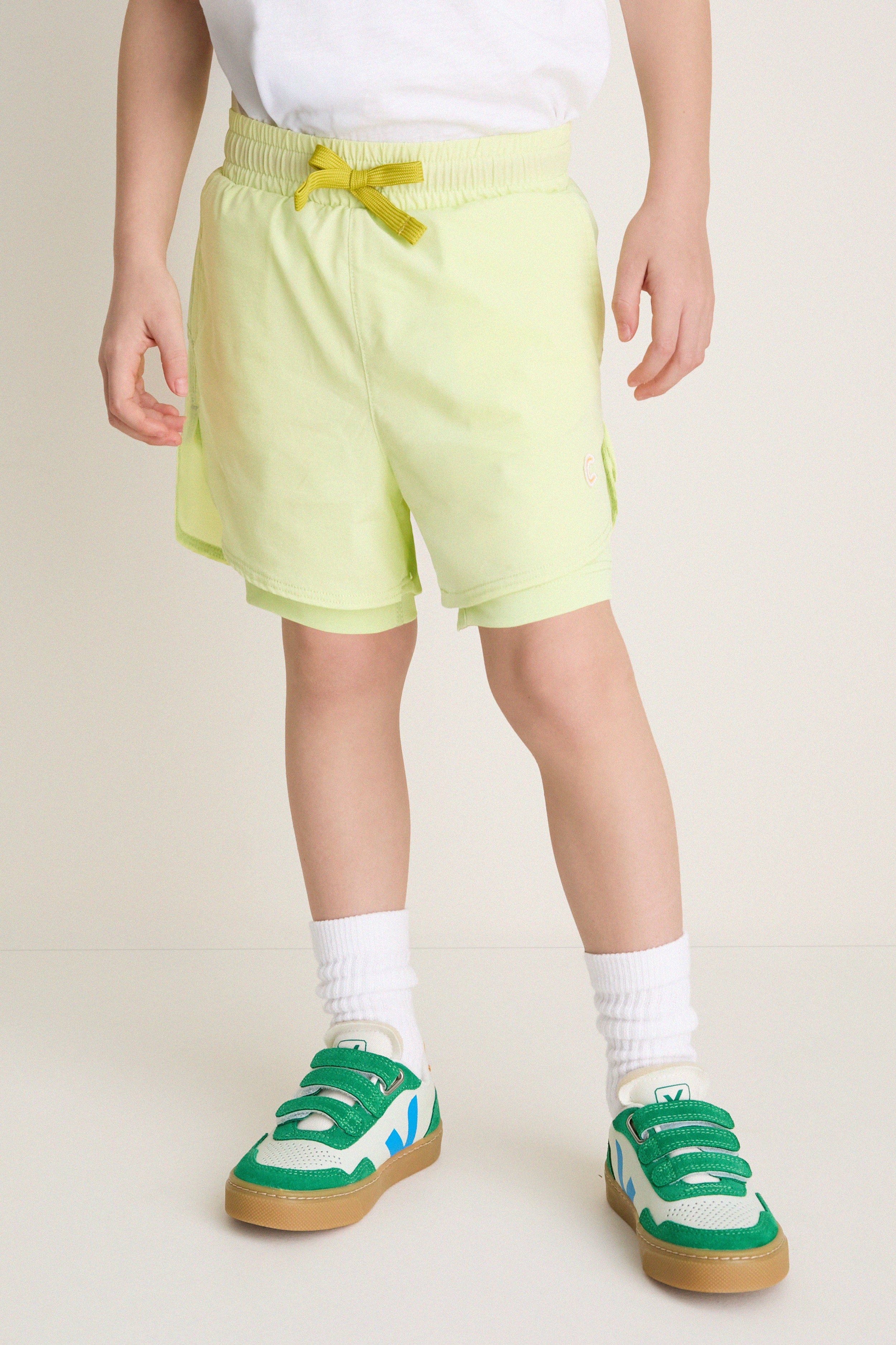 Child mannequin in Citron Zest Cardio Short, blending classic athletic style with effortless fun. Paired with white socks and sneakers, perfect for active, high-end comfort.