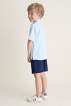 Young boy in profile wearing Nautical Navy Le Club Short and striped polo, embodying classic, effortless style with high-end, fun appeal. Perfect for polished, everyday wear.