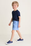 Young boy wearing Sardinia Sky Le Club Short and navy sneakers, mid-step, embodying a classic, effortless style; perfect for high-end, fun everyday wear.