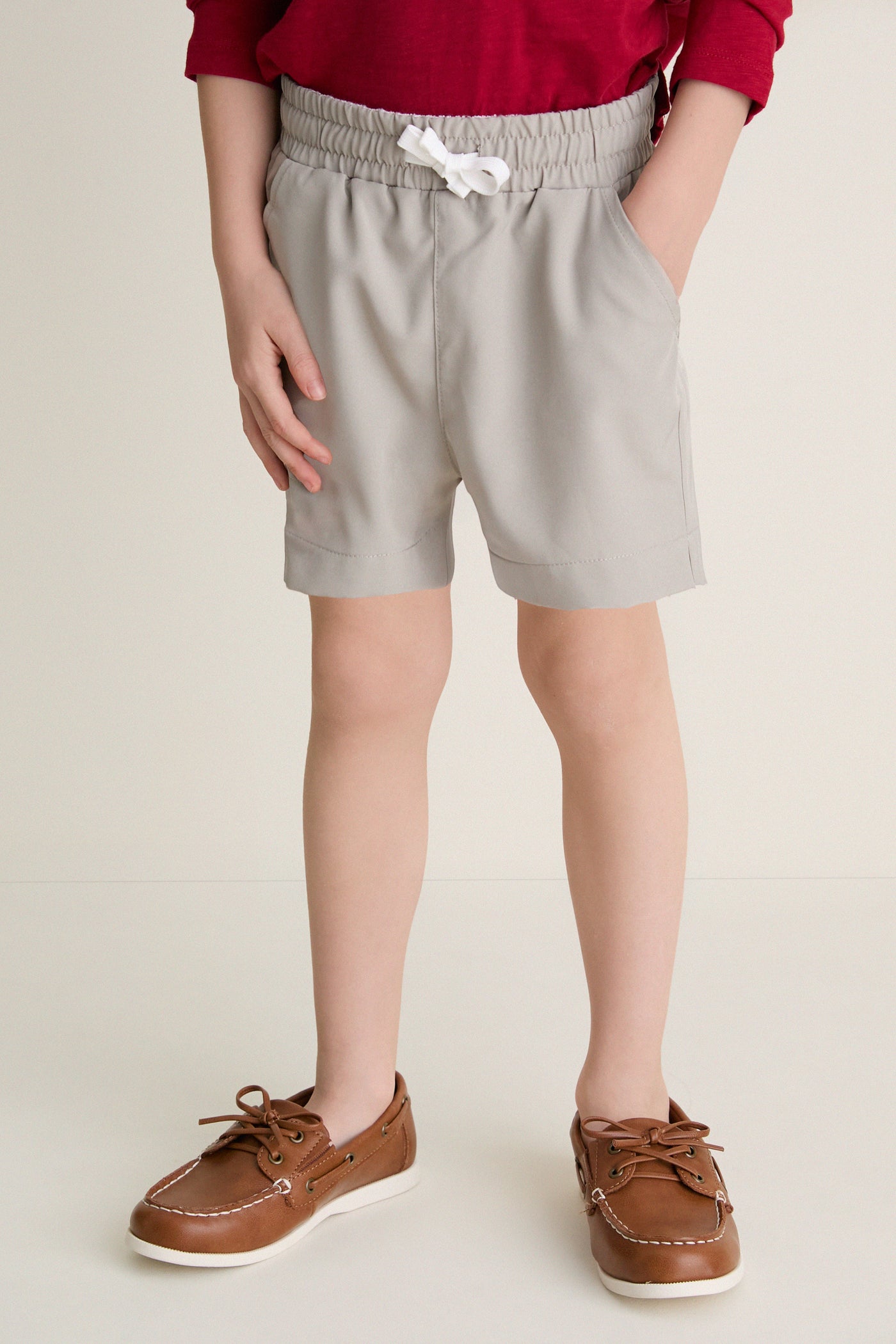 Child wearing classic Patagonian Putty Le Club Shorts with elastic waist and white drawstring; paired with boat shoes, capturing an effortless, high-end, and fun style for warm-weather adventures.
