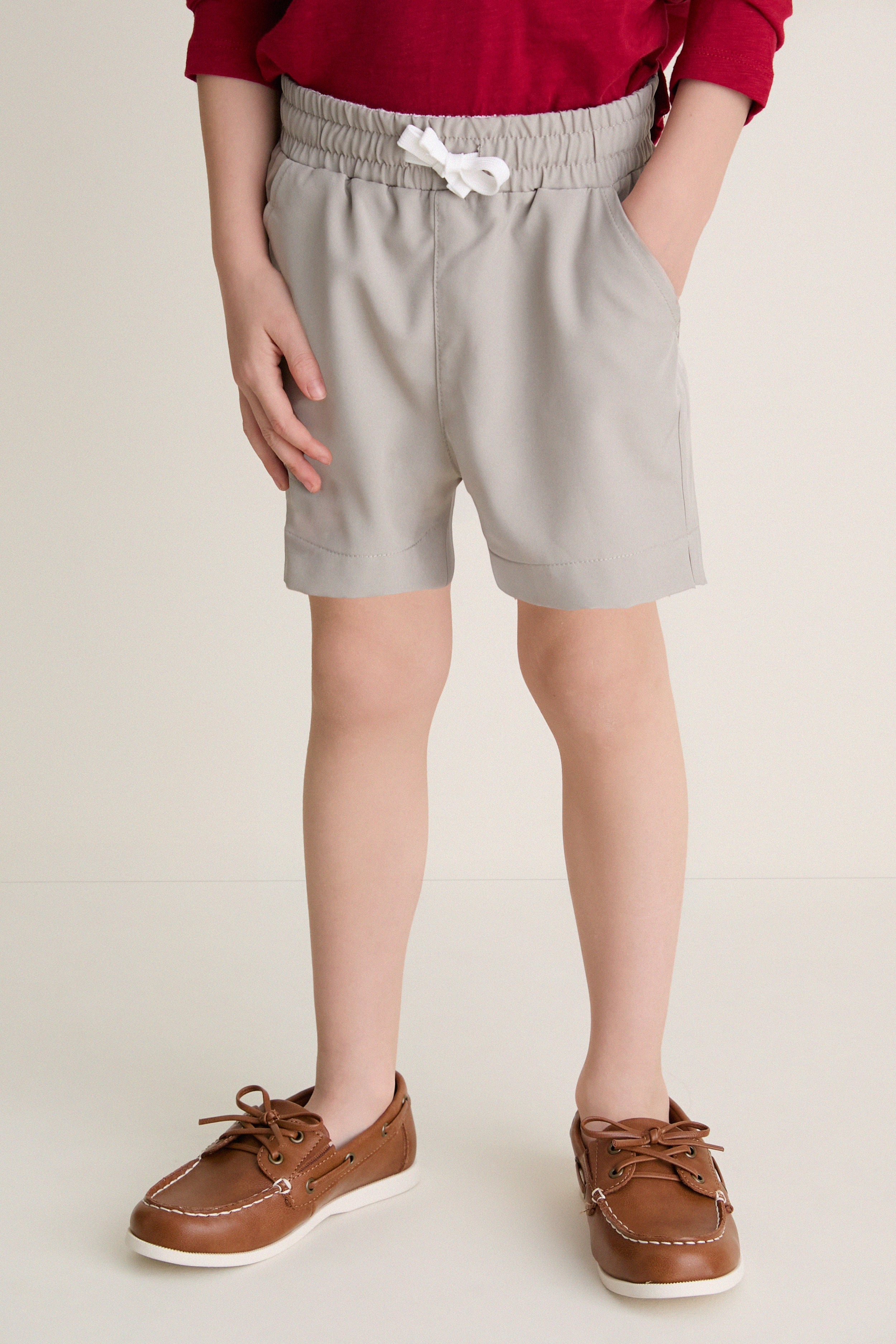 Child wearing classic Patagonian Putty Le Club Shorts with elastic waist and white drawstring; paired with boat shoes, capturing an effortless, high-end, and fun style for warm-weather adventures.