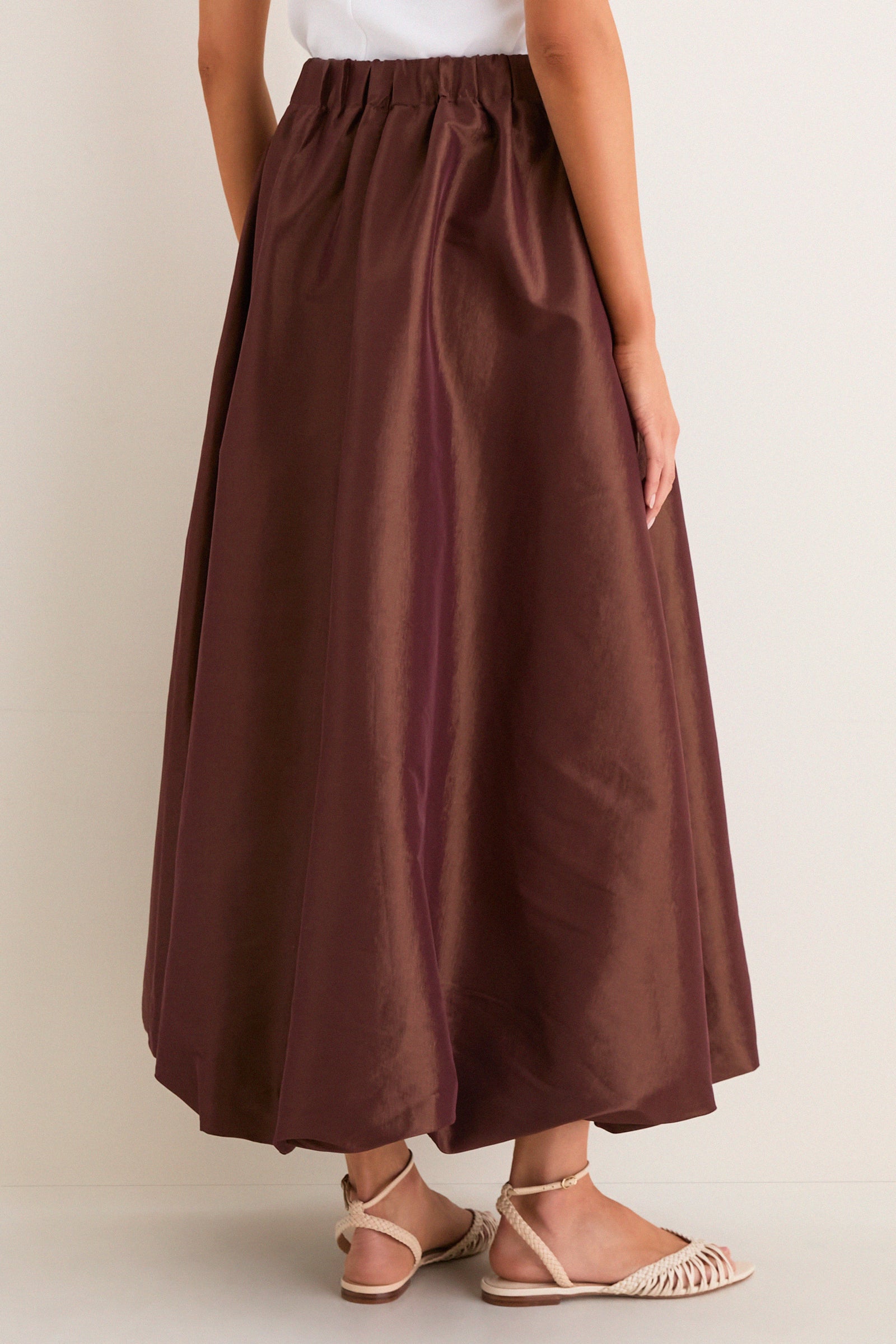 Effortless classic style with the Chestnut Taffeta Cynthia Bubble Skirt, featuring a bubble hem and elastic waistband, paired with woven sandals for a high-end, fun look.