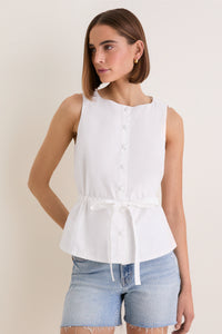 Young woman in a classic, sleeveless White Cotton Poplin Francoise Top with a high neckline and self-tie waist, paired with light-wash denim shorts, exuding effortless elegance.