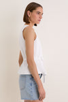 Young woman in profile wearing the White Cotton Poplin Francoise Top, featuring a high neckline and cinched waist; paired with a denim mini-skirt for classic, effortless style.