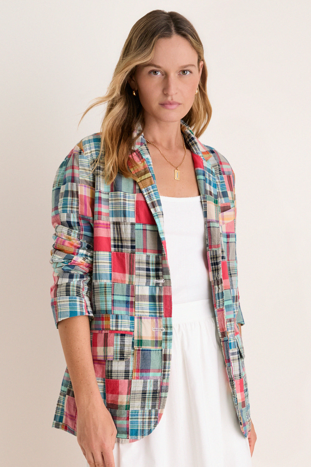 Woman in a white tank and skirt in a madras blazer. 
