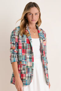 Woman in a white tank and skirt in a madras blazer. 