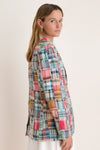 Woman turned to the side in a madras blazer and a white skirt. 