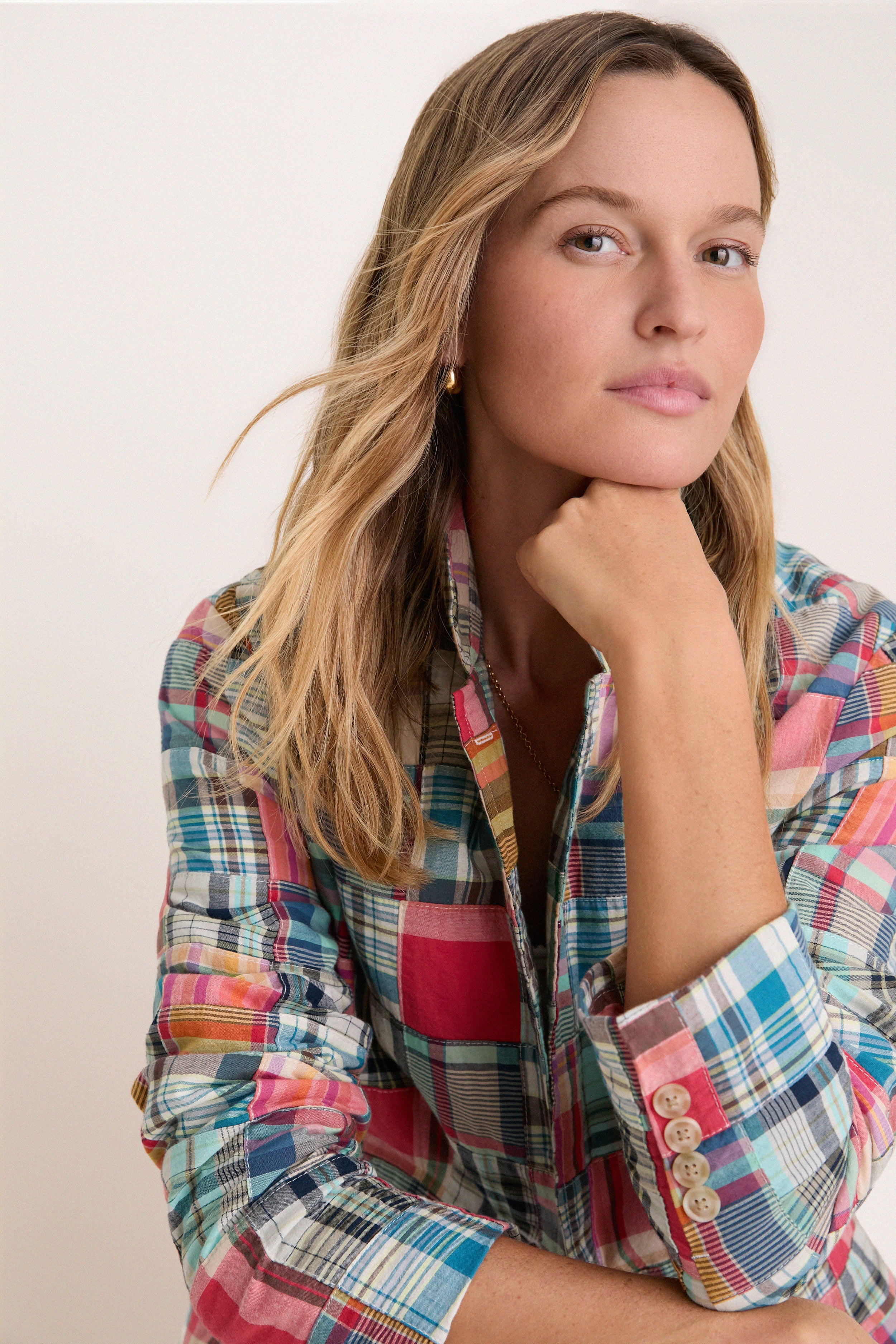 Closeup of woman in a madras blazer with the collar pulled up. 