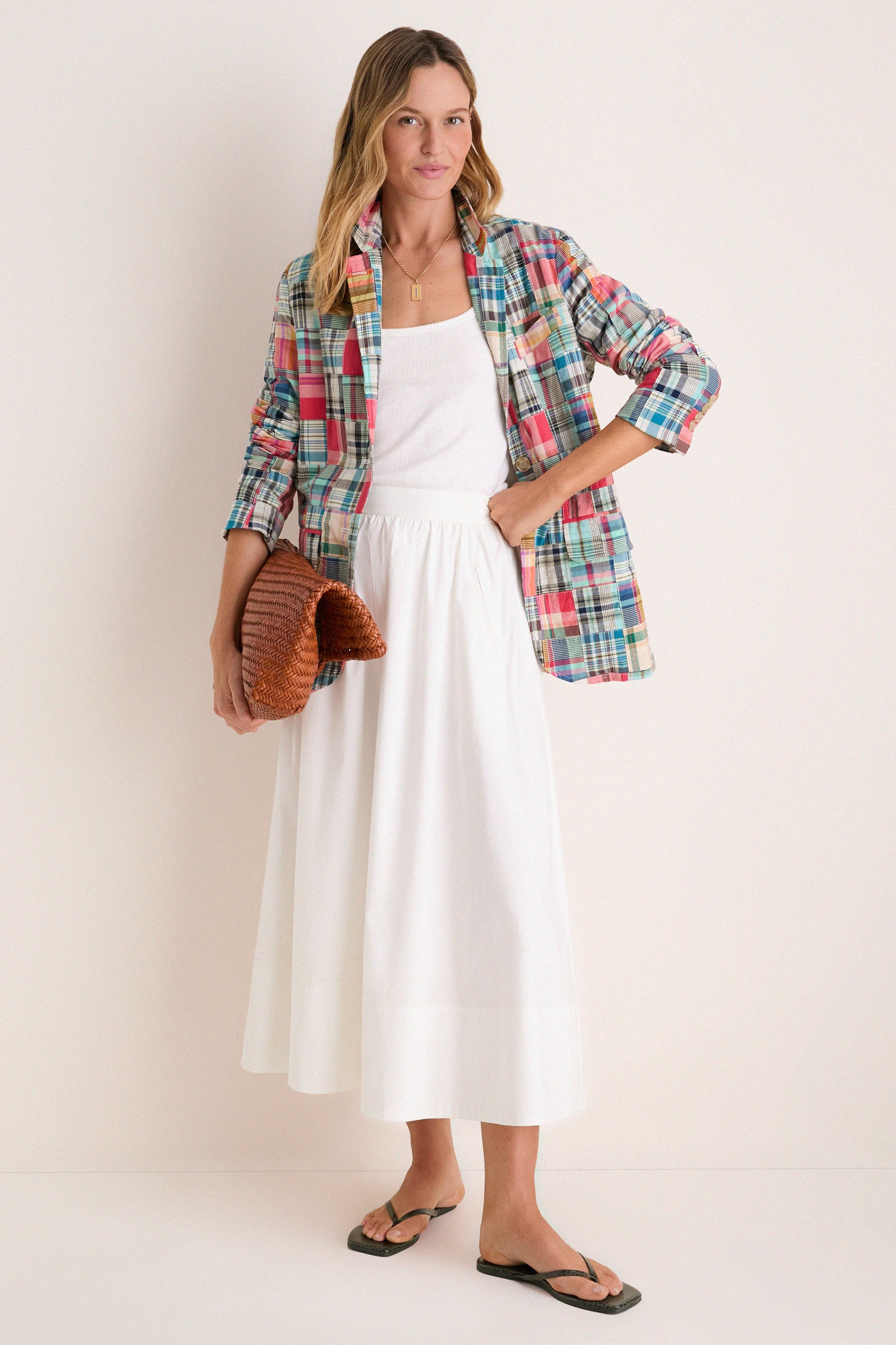 Woman in a white tank and skirt in a madras blazer. 