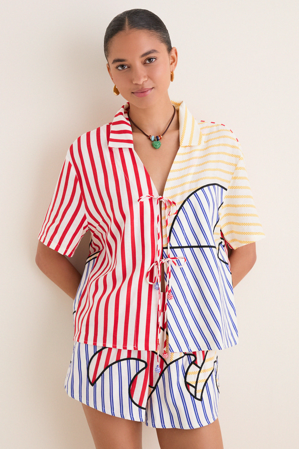 Young woman in a classic, effortless Navy Stripes Off-White Tie Front Blouse with playful multi-colored stripes, embodying high-end, fun style.