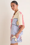 Young woman wearing the classic, effortless Navy Stripes Off-White Tie Front Blouse, featuring fun multi-colored stripes and high-end details, exuding a relaxed, playful charm.