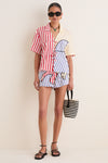 Model in the Navy Stripes Off-White Tie Front Blouse with matching shorts, exuding an effortless, fun vibe. A classic, high-end summer look completed with black sandals and a woven tote.