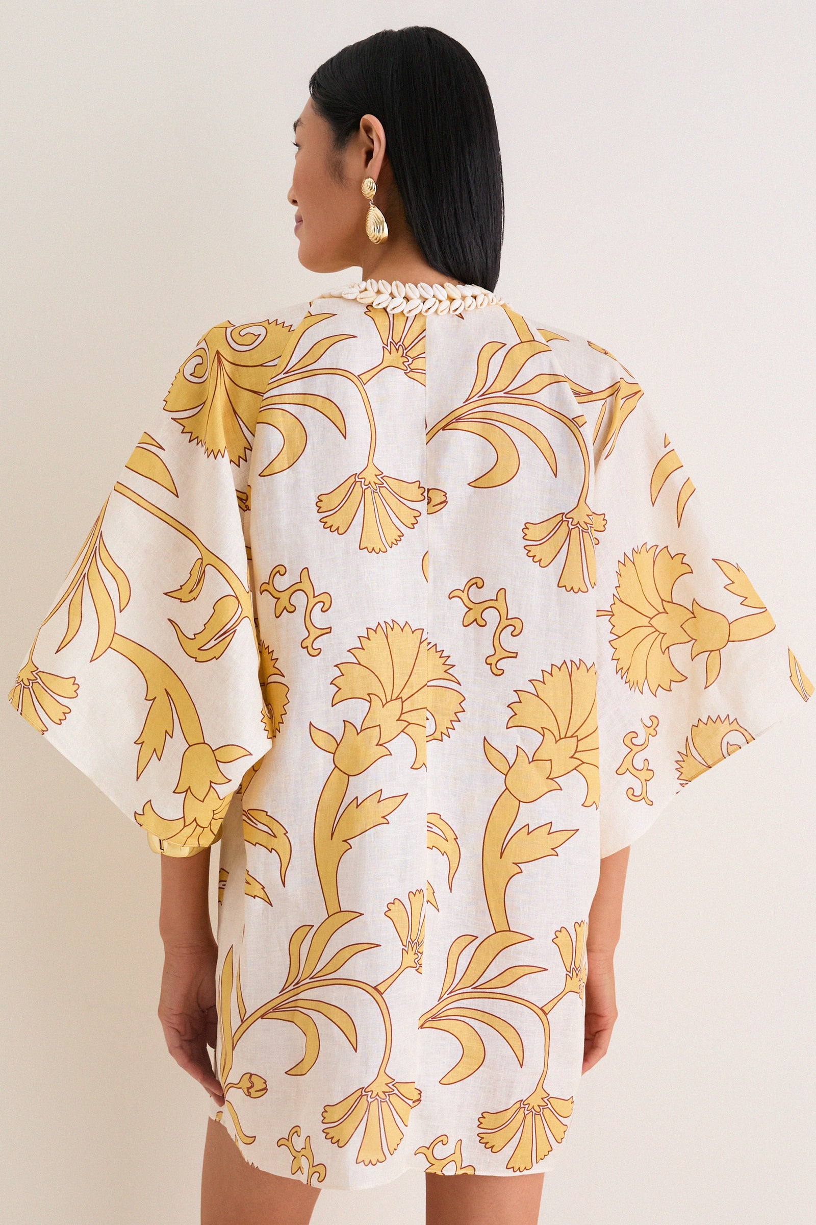 Woman wearing Yellow Flowers Andina Hand-Embroidered Linen Mini Tunic with classic wide sleeves, effortless fit, and fun shell details, exuding a high-end, relaxed elegance.