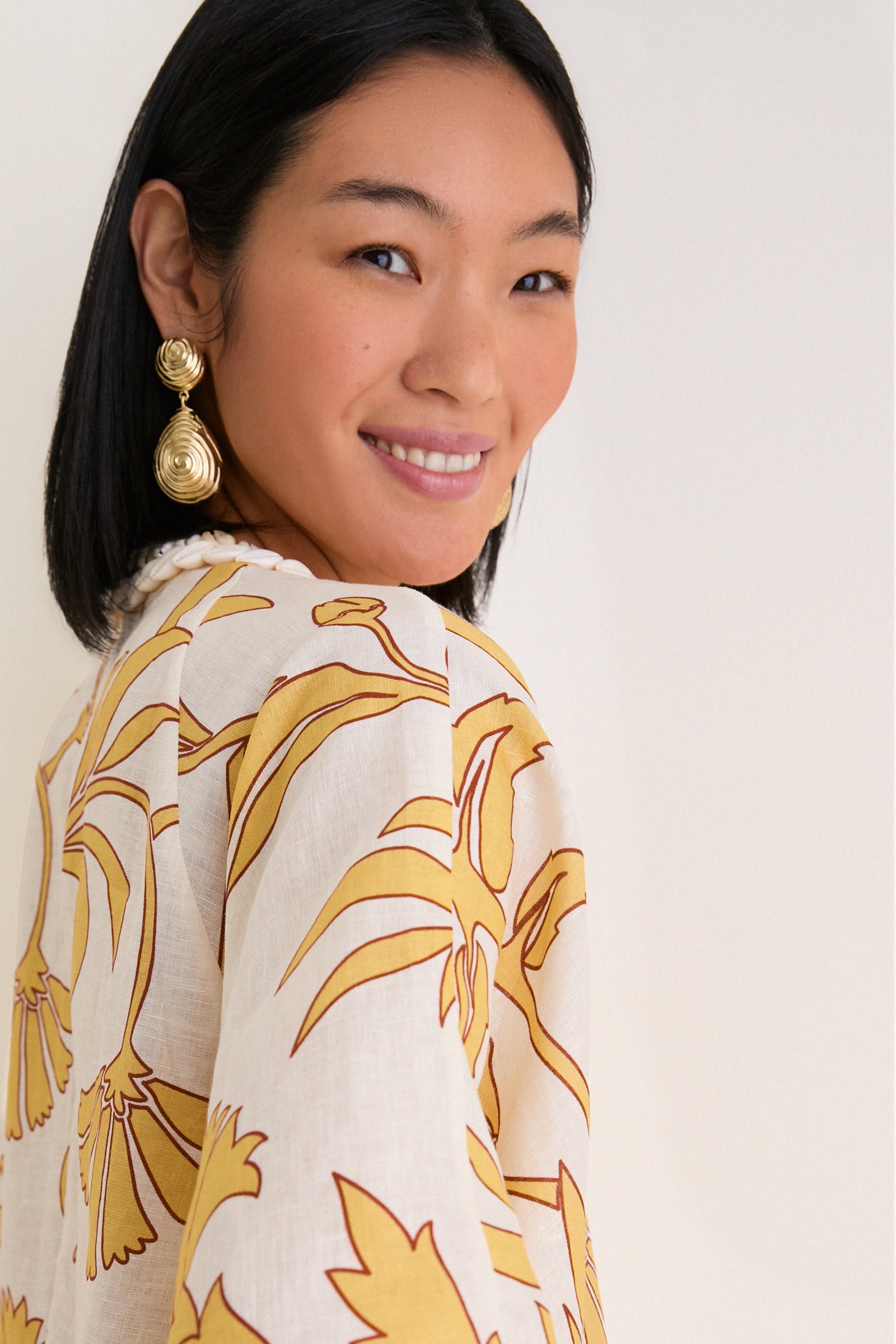Woman wearing the Yellow Flowers Andina Hand-Embroidered Linen Mini Tunic, showcasing its classic, effortless style with a relaxed fit and fun, high-end, yellow floral pattern.