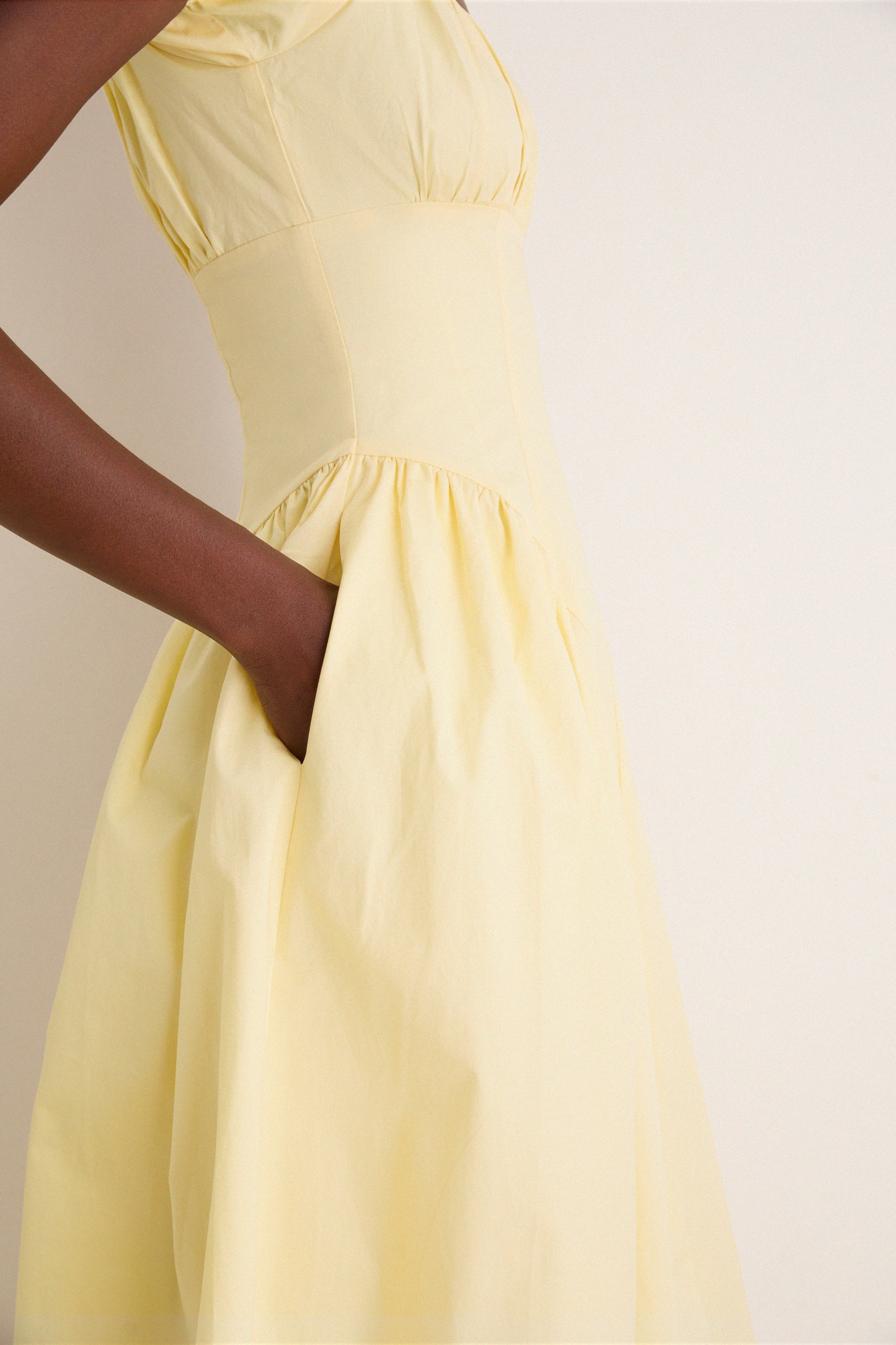 Close-up of a person wearing the classic Yellow Adilene Midi Dress, showcasing its effortless fit and flare design with a fun hidden pocket detail.