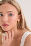 Young woman with classic, high-end Gold Molten Gemstone Baguette Dome Small Hoop Earrings featuring green onyx, embodies effortless elegance and fun sophistication.