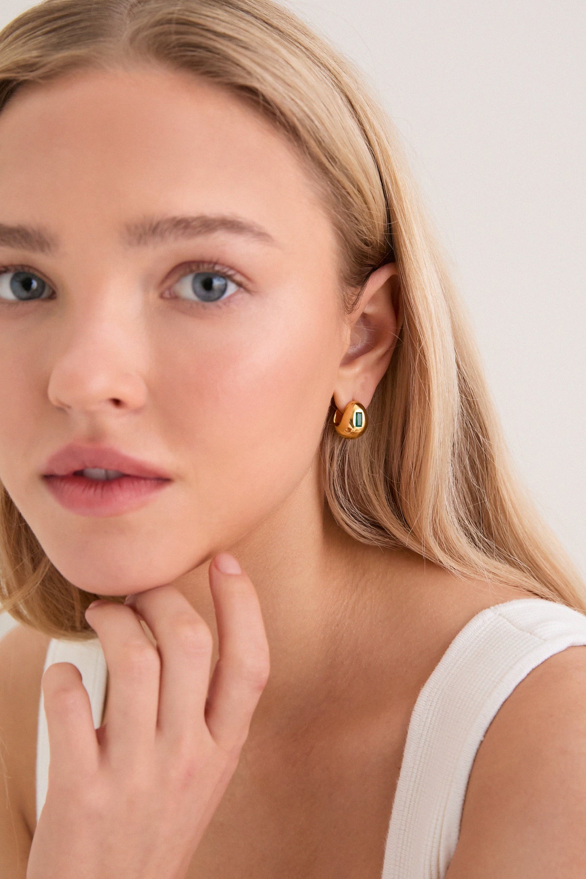 Young woman with classic, high-end Gold Molten Gemstone Baguette Dome Small Hoop Earrings featuring green onyx, embodies effortless elegance and fun sophistication.