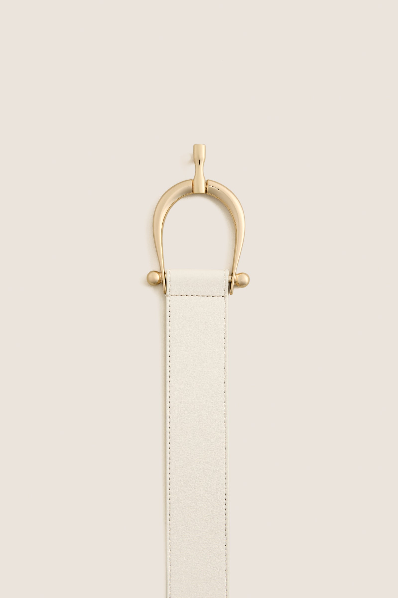 Gesso Grant Belt featuring a classic off-white leather strap with an elegant gold-tone clasp, exudes effortless high-end style, ideal for versatile, fun fashion statements.