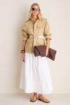 Woman models a classic, high-end look featuring the Gesso Grant Belt with equestrian-style buckles, effortlessly cinching a safari-style jacket over a flowing skirt.