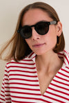 Young woman wearing classic Black Leonard Sunglasses by Illesteva, round silhouette and chic style, embodying an effortless, high-end look with fun, everyday versatility.