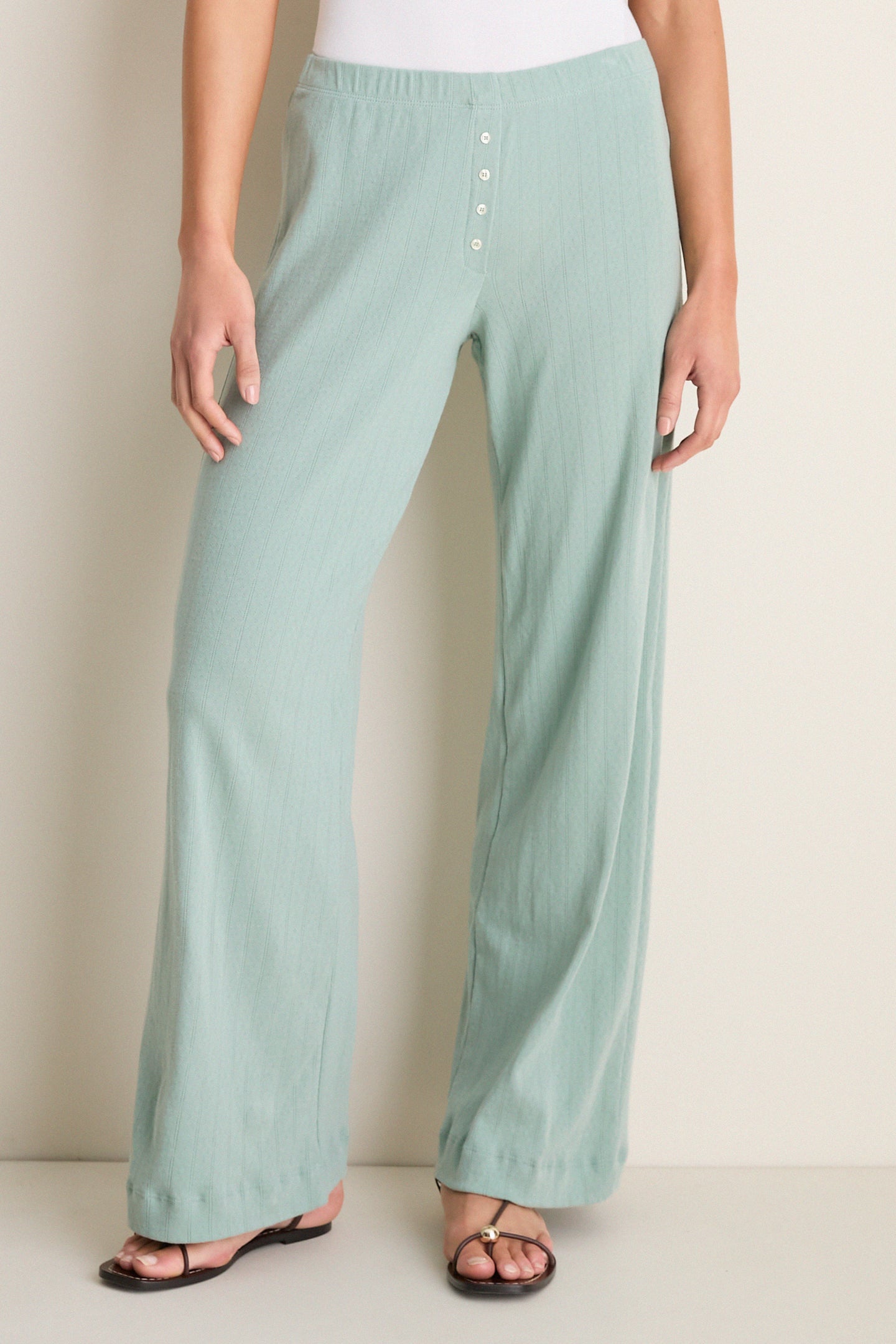 Person wearing Eucalyptus Pointelle Boxer Pants with wide-leg, relaxed fit, and button details, paired with flat thong sandals for an effortless, classic, high-end look.