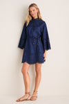 Model in Ink Mahon Broderie Denim Mini Dress with scalloped collar and bell sleeves, embodying classic elegance. Styled with flat sandals for an effortless, high-end daytime look.