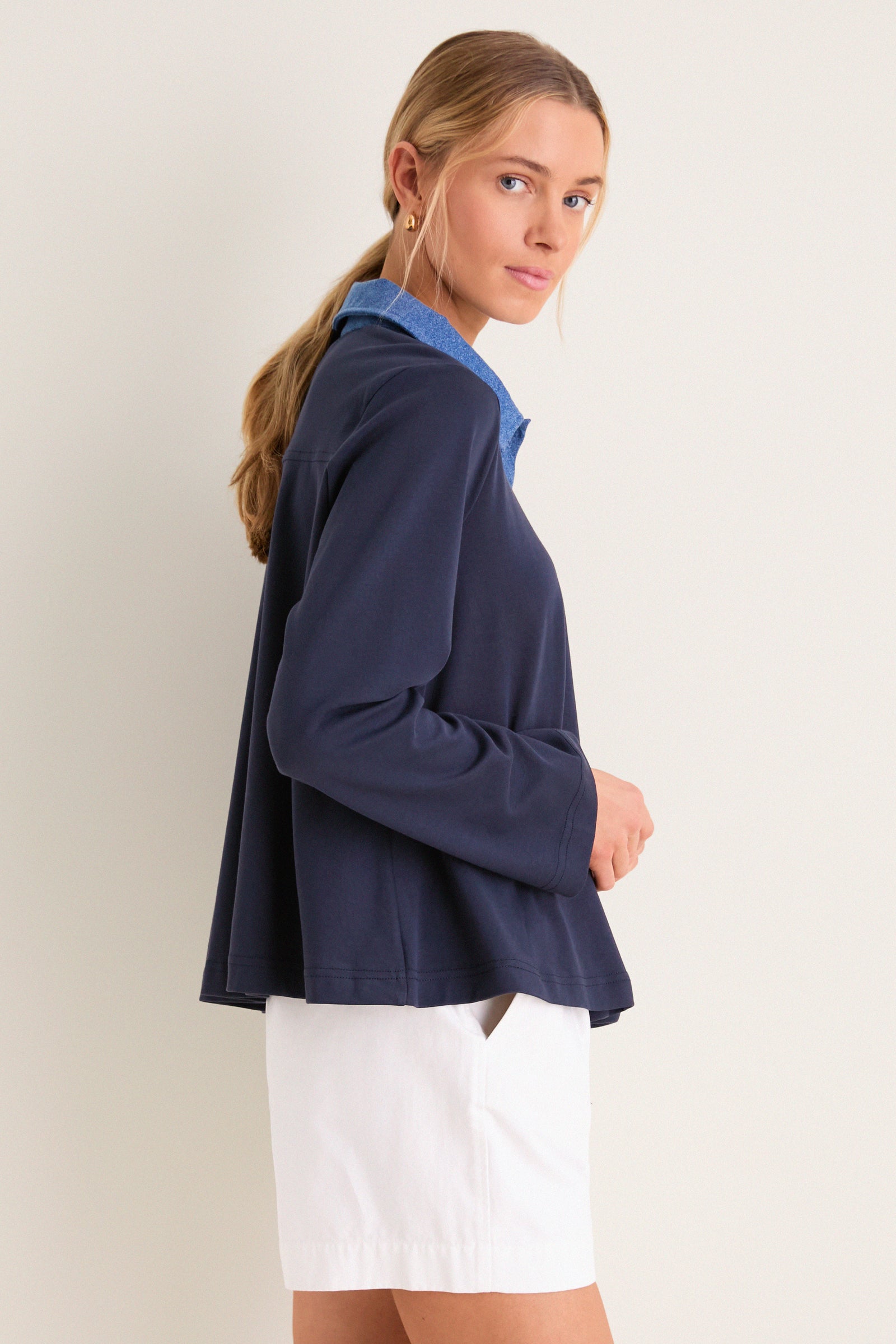 Young woman models the classic, high-end Denim Collar Carlyn Long Sleeve Polo, showcasing its effortless style with playful denim accents and a fun, relaxed fit.