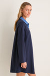 Young woman modeling the Denim Collar Carolyn Swing Mini Dress, showcasing its classic and effortless style. The dress exudes fun and high-end appeal with its distinctive design.