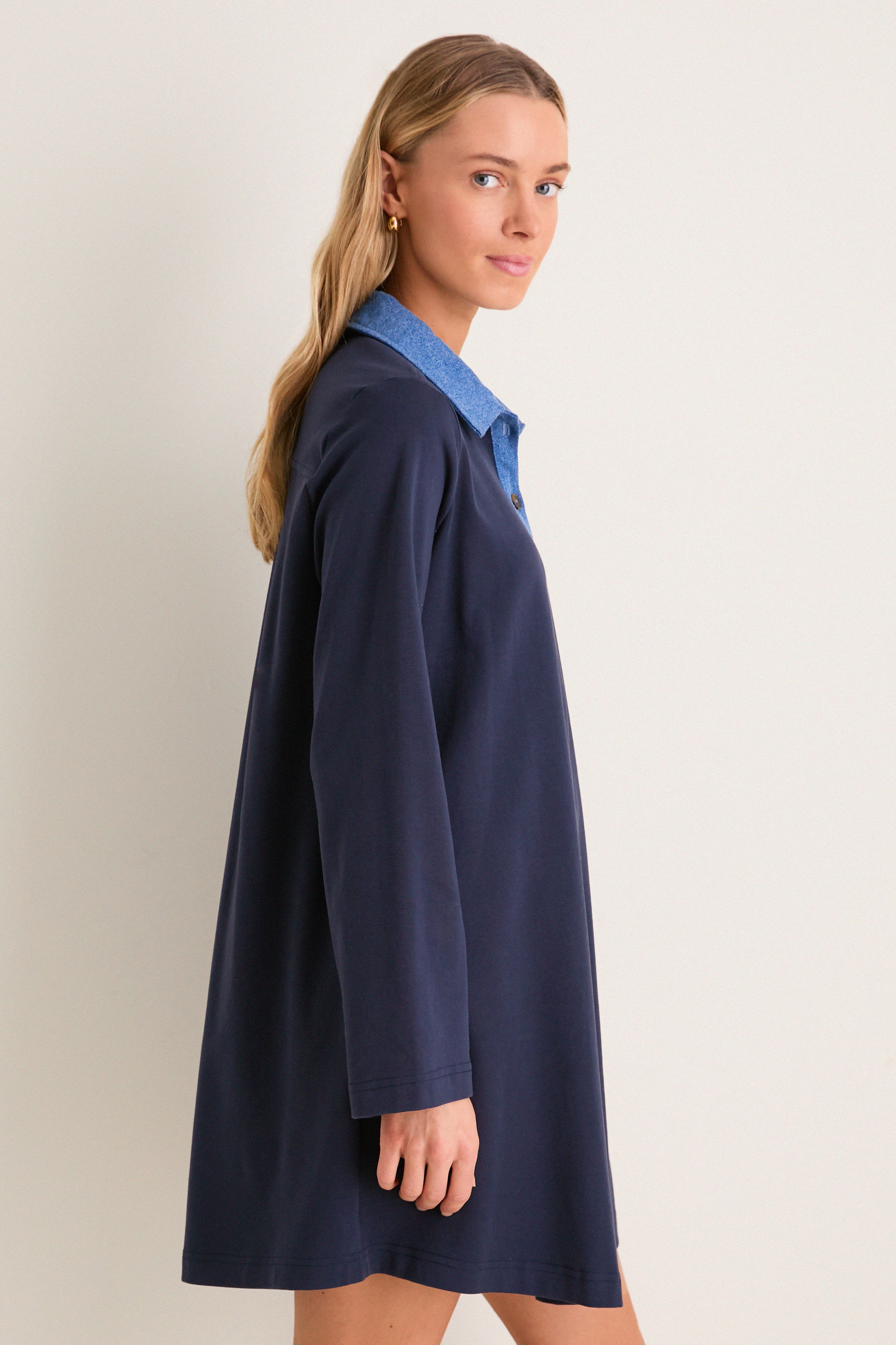 Young woman modeling the Denim Collar Carolyn Swing Mini Dress, showcasing its classic and effortless style. The dress exudes fun and high-end appeal with its distinctive design.