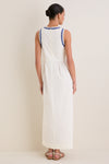Woman in a classic, sleeveless White Ric Rac Tie-Front Brocks Dress with wavy blue trim, embodying an effortless and high-end style, paired with fun, simple white sandals.