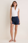 Model wearing the classic White Sleeveless Bessette Button Down, paired with navy shorts and tan sandals, exuding an effortless, high-end, and fun summer style.