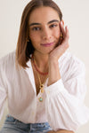 Young woman wearing a classic White Shadow Stripe Juliette Button Down with billowy sleeves and effortless stripes, exuding a fun, high-end style paired with delicate necklaces.