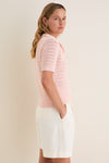 Young woman in profile wearing the classic Pink Crochet Cotton Asher Polo, showcasing its effortless, high-end style paired with high-waisted shorts, embodying fun elegance.