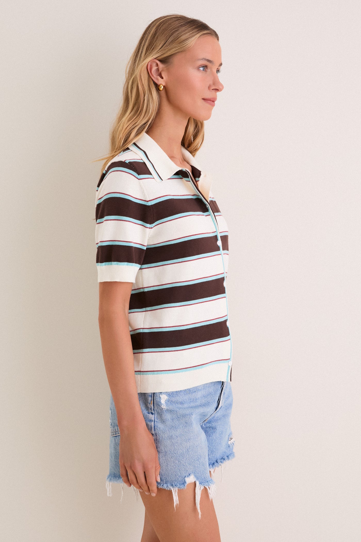 Young woman in a Mint Chocolate Stripe Reid Polo Cardigan with button-front, short sleeves, and collared neckline, paired with denim shorts, exuding classic, effortless style.