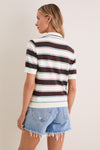 Woman in a classic Mint Chocolate Stripe Reid Polo Cardigan with bold stripes, embodying effortless and fun style, paired with high-end frayed denim shorts.