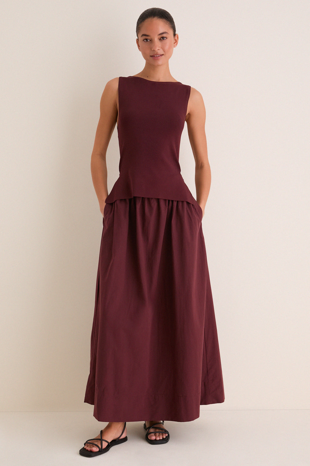 Woman in Dark Cherry Boatneck Mix Media Midi Dress with side pockets, styled effortlessly with black sandals for a classic, high-end look, perfect for fun day-to-night transitions.